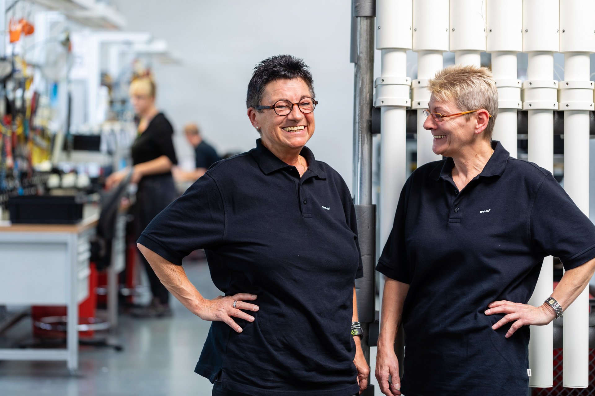 Two female WE-EF employees smiling and talking to each other in the factory."