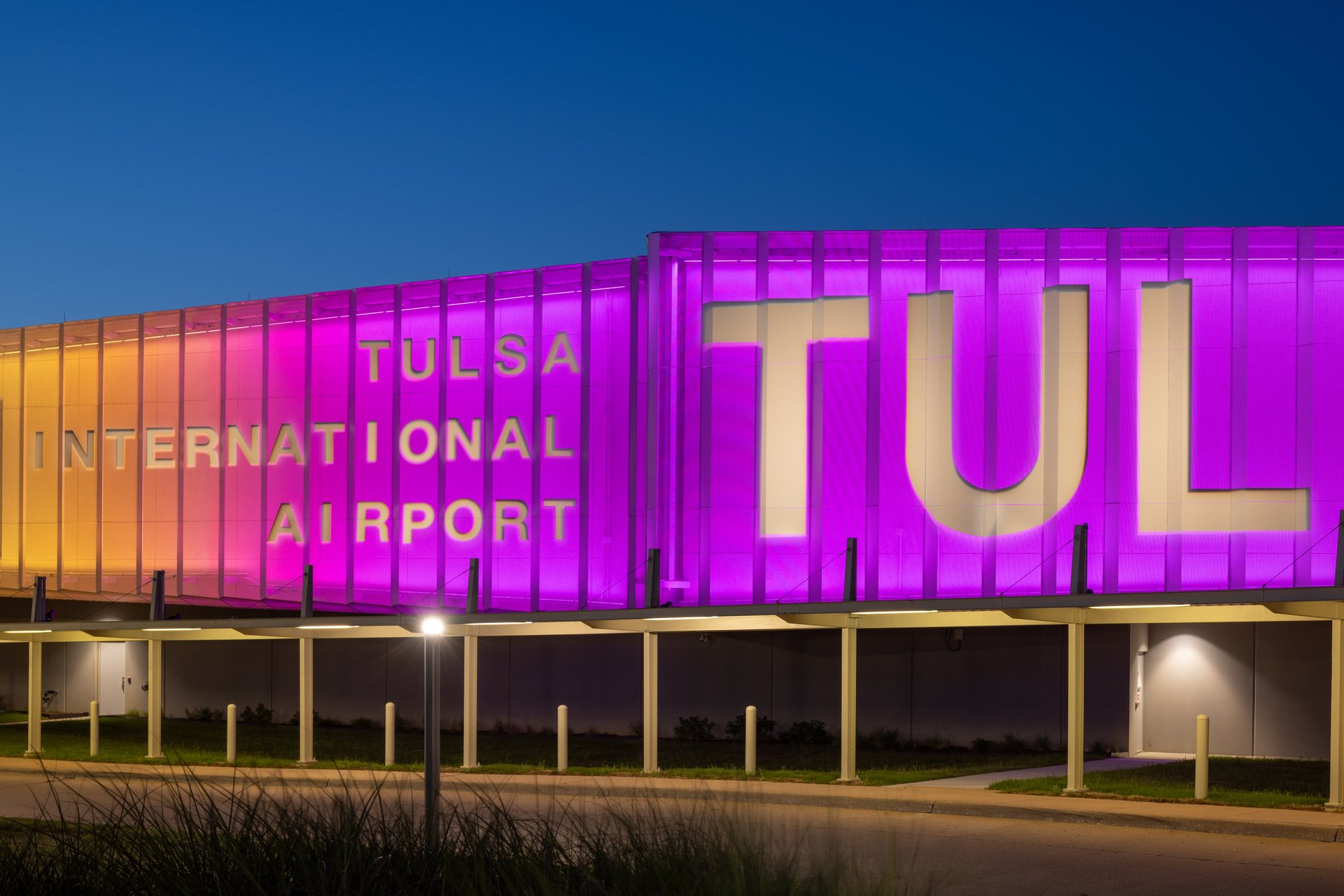 Facade of Tulsa International Airport is lit in purple and pink light. 