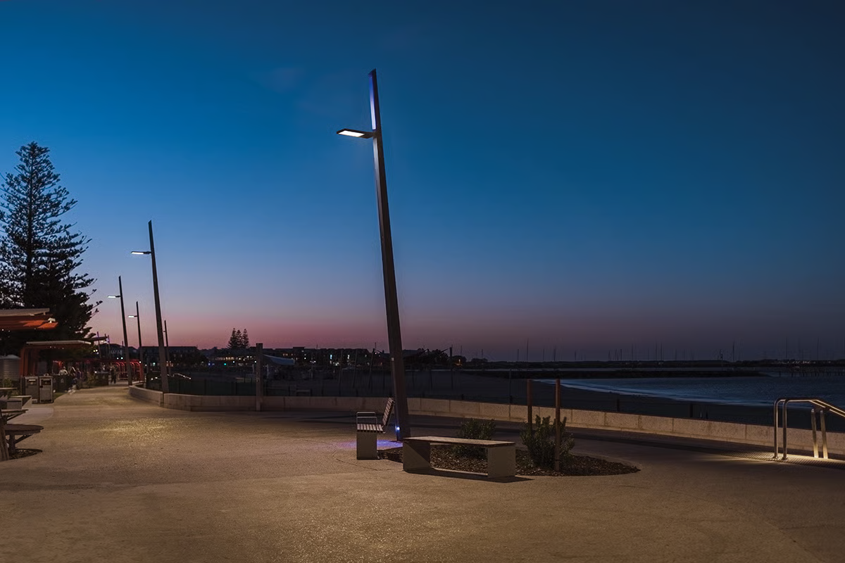 Koombana Bay Foreshore illuminated at twilight with WE-EF VFL540 LED street and area luminaires providing warm-toned pathway lighting along waterfront promenade, demonstrating environmentally sensitive lighting design using warmer color temperatures with reduced blue-violet wavelengths to minimize disruption to migratory marine species like turtles while ensuring safe pedestrian access to coastal public spaces