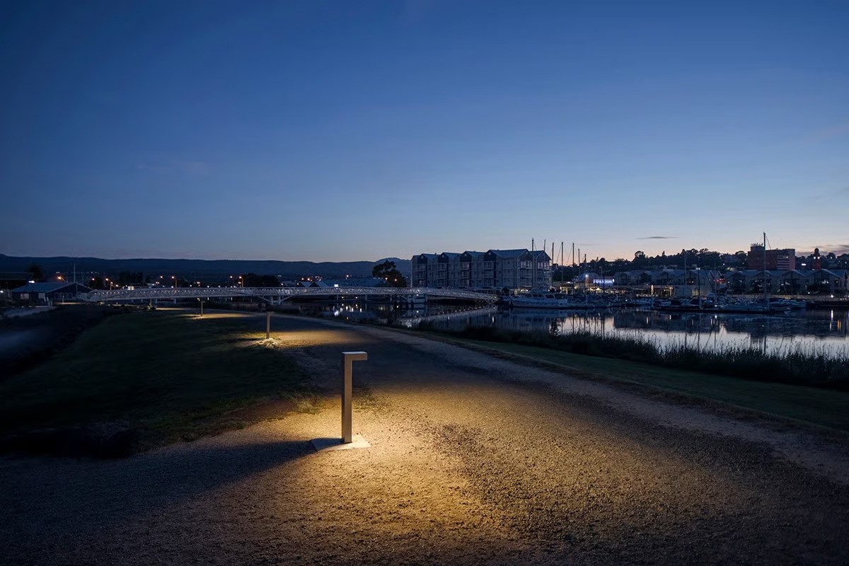 Close-up of WE-EF VFL540 bollard luminaire with green LED illumination providing vandal-proof lighting and minimizing light pollution at Riverbend Park waterfront