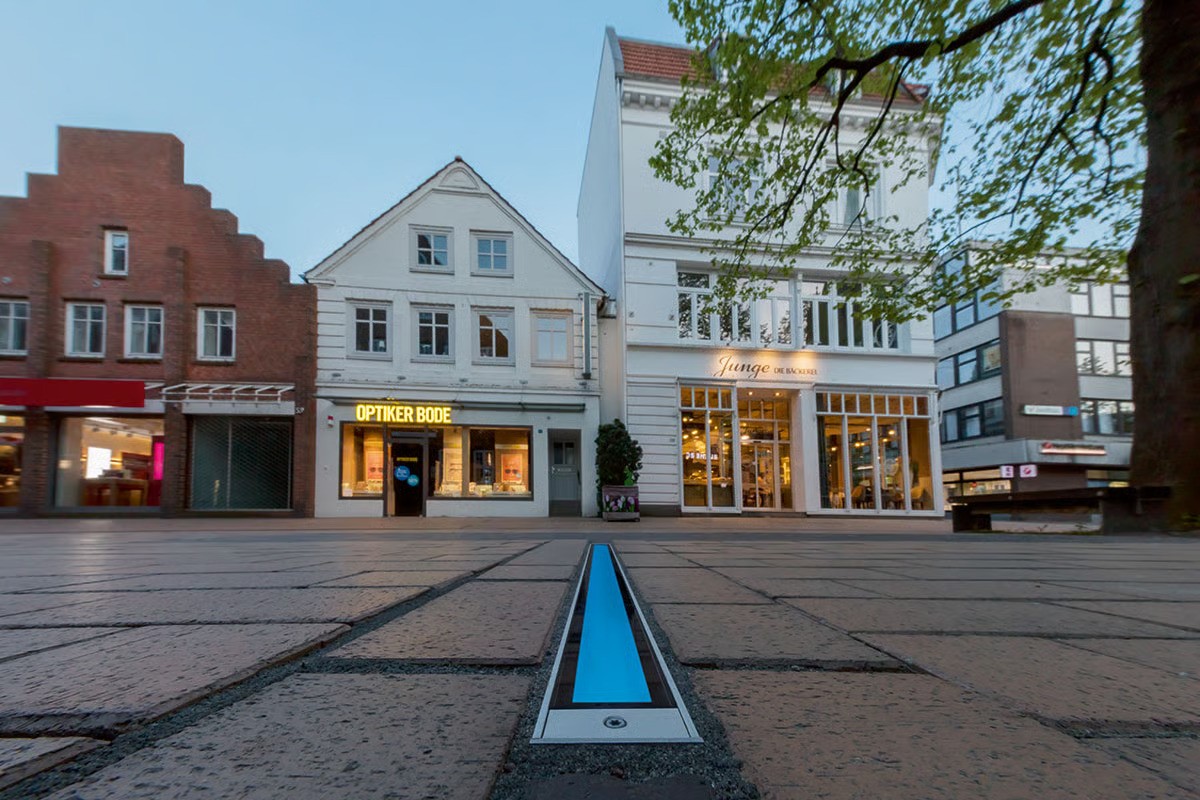 WE-EF ETV130 33W inground luminaire with blue LED light and DMX control creating orientation line in historic Elmshorn town center Germany