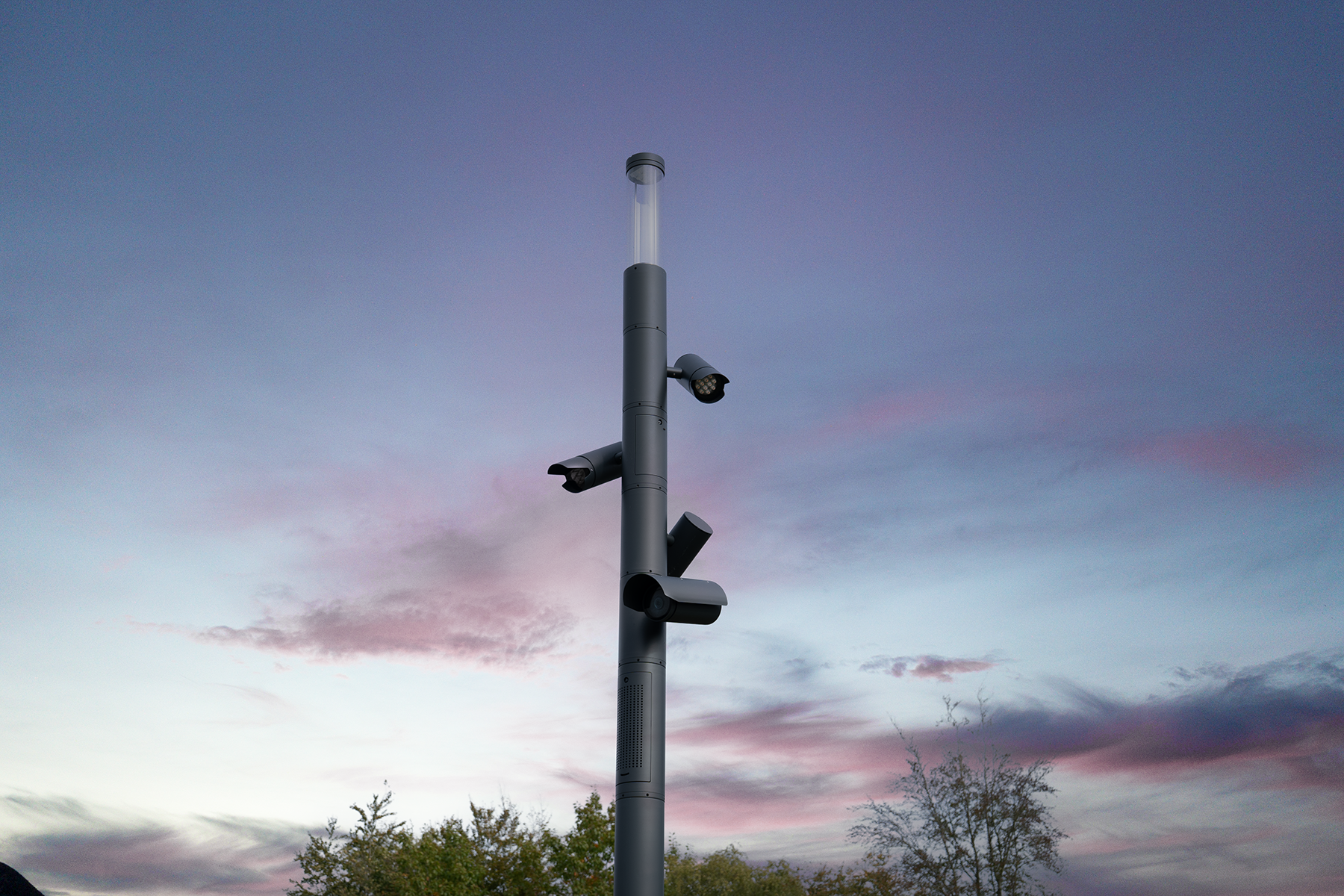 Smart city lighting pole with integrated digital technologies, sensors and communication systems in an urban plaza at dusk.