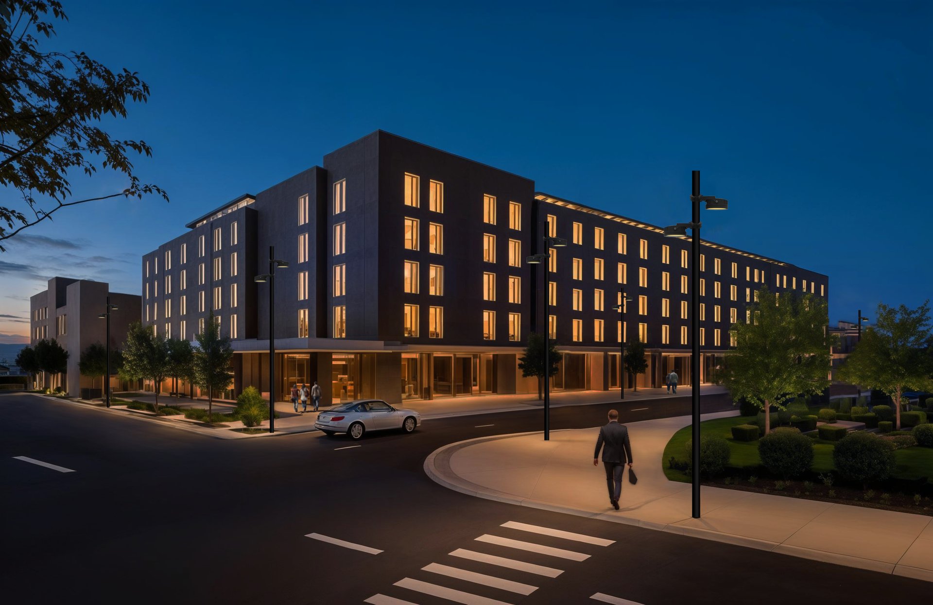 Modernes Stadtquartier bei Dämmerung mit gleichmäßig ausgeleuchteter Fassadenarchitektur, Straßenraum und Gehwegen – präzise Außenbeleuchtung unterstreicht Architektur, Orientierung und Aufenthaltsqualität im urbanen Umfeld.