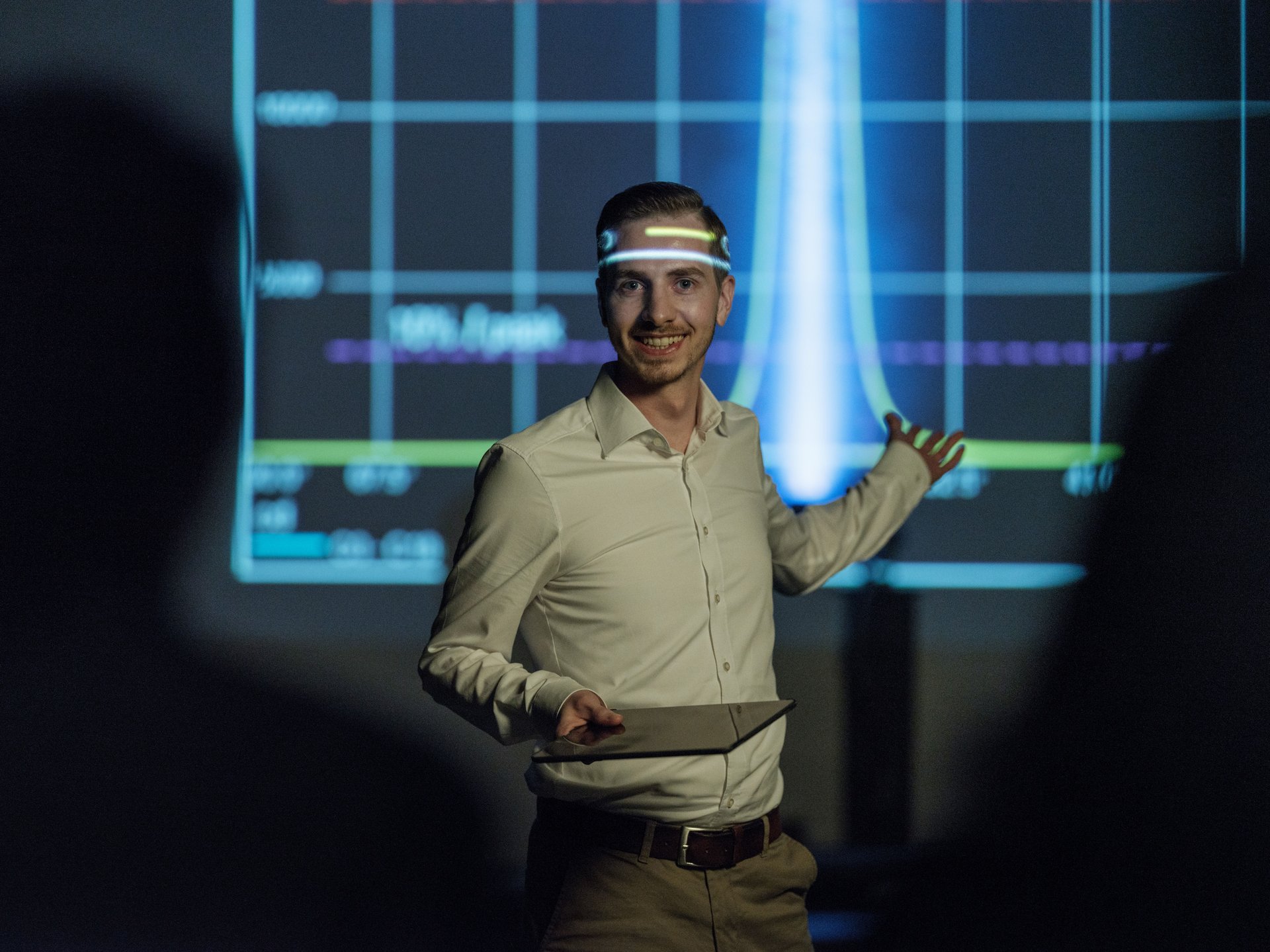 Ein WE-EF-Teammitglied präsentiert lichttechnische Eigenschaften von WE-EF-Produkten, während die Projektion interessante Lichteffekte auf sein Gesicht wirft.