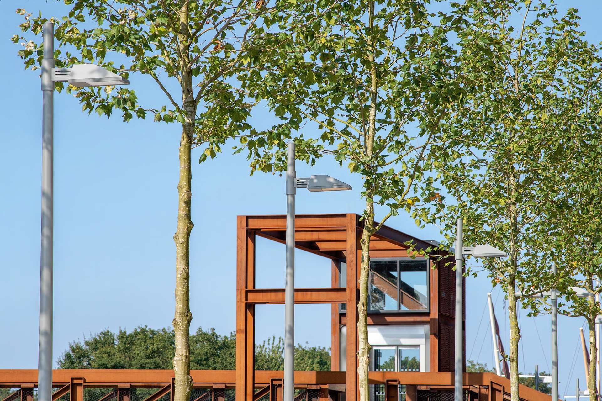 Hale Wharf children's play area with timber play structure and young plane trees, WE-EF PFL230 LED pole-mounted luminaires on 4.5-meter and 6-meter poles with single and double-arm brackets providing standards-compliant illumination of traffic-calmed residential common spaces, designed by Landscape Projects for affordable housing development on former industrial wasteland near Tottenham