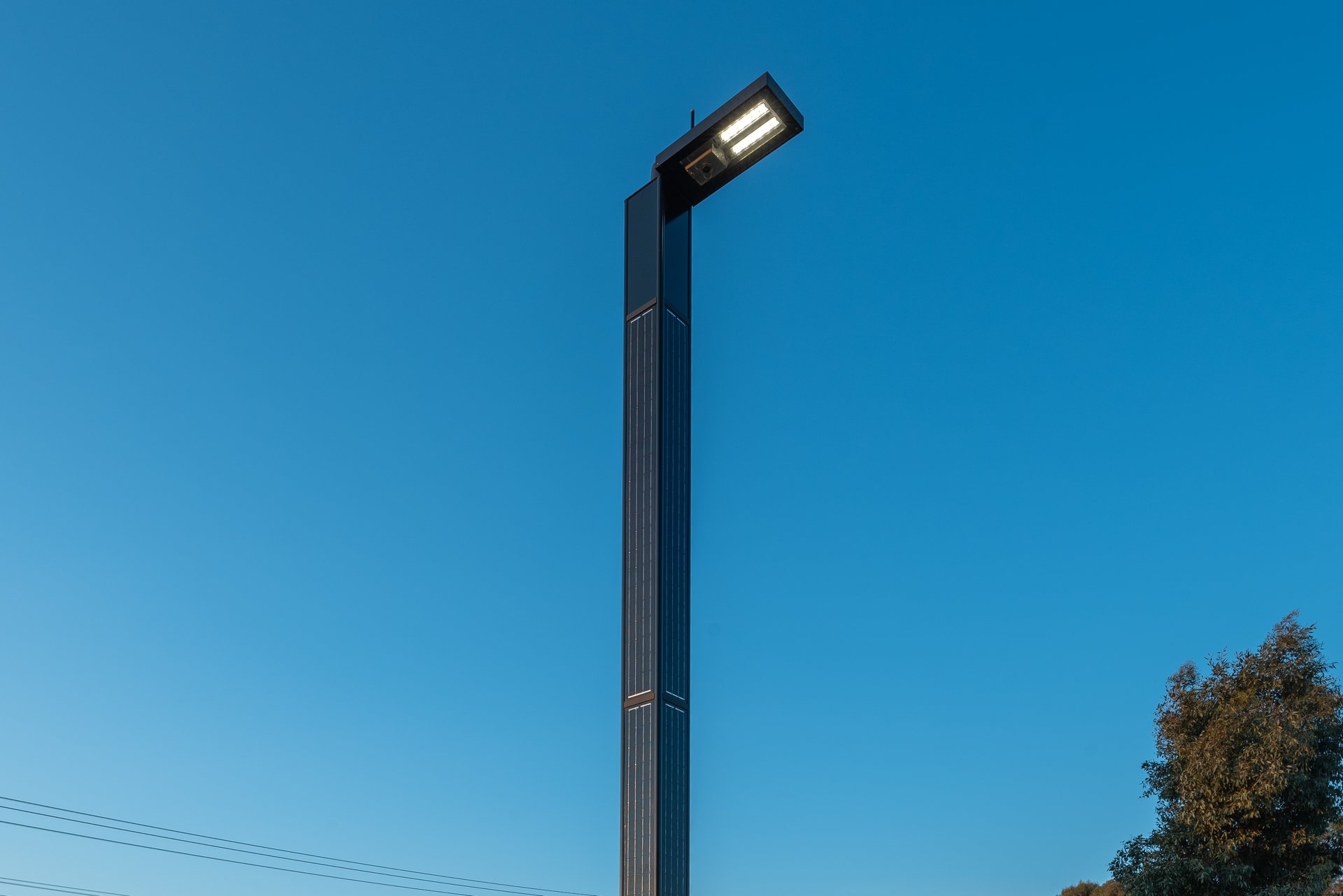 pole with solar panels on all sides, the luminaire at the top is lit