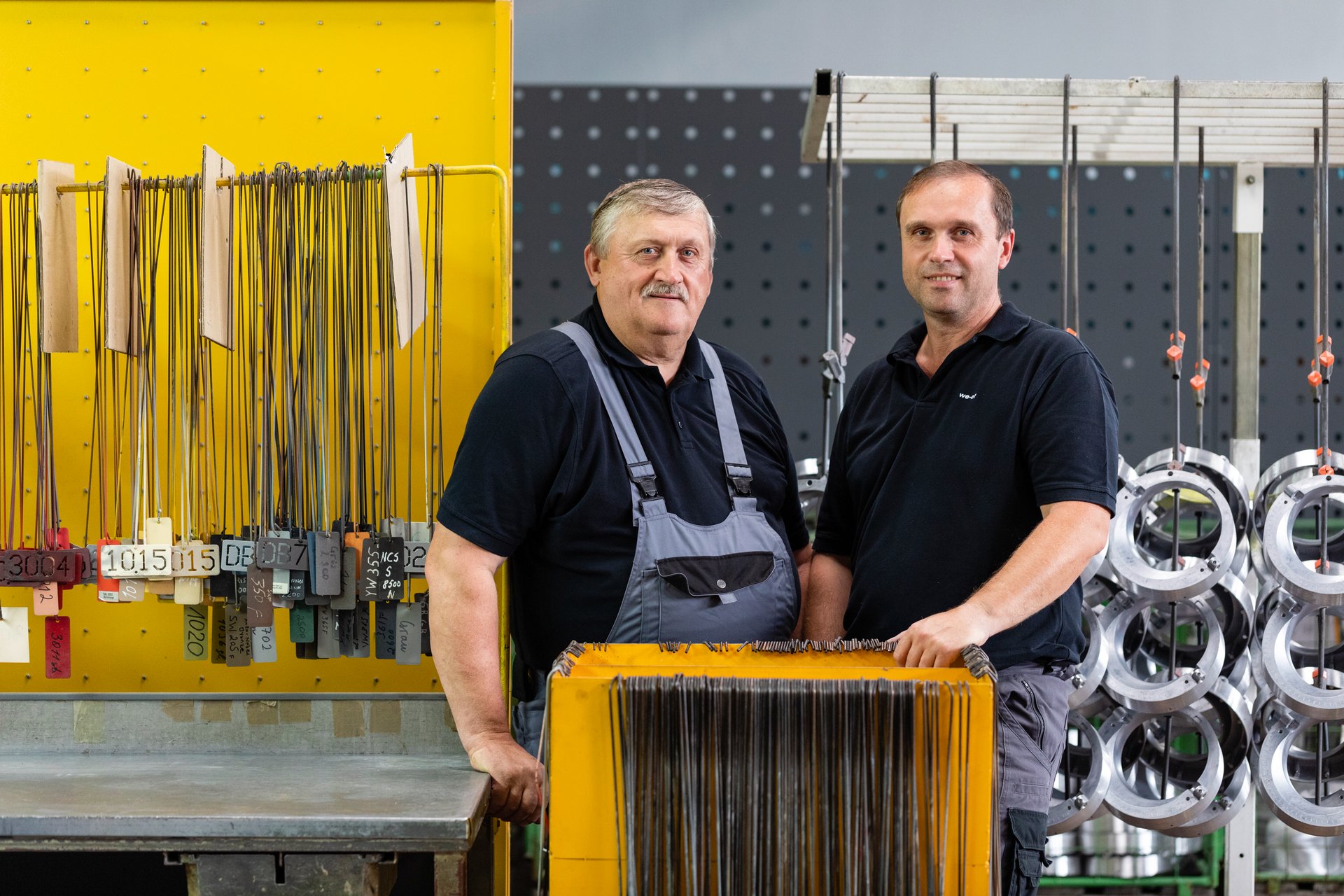 Deux ouvriers d’usine posent dans un atelier en regardant la caméra."