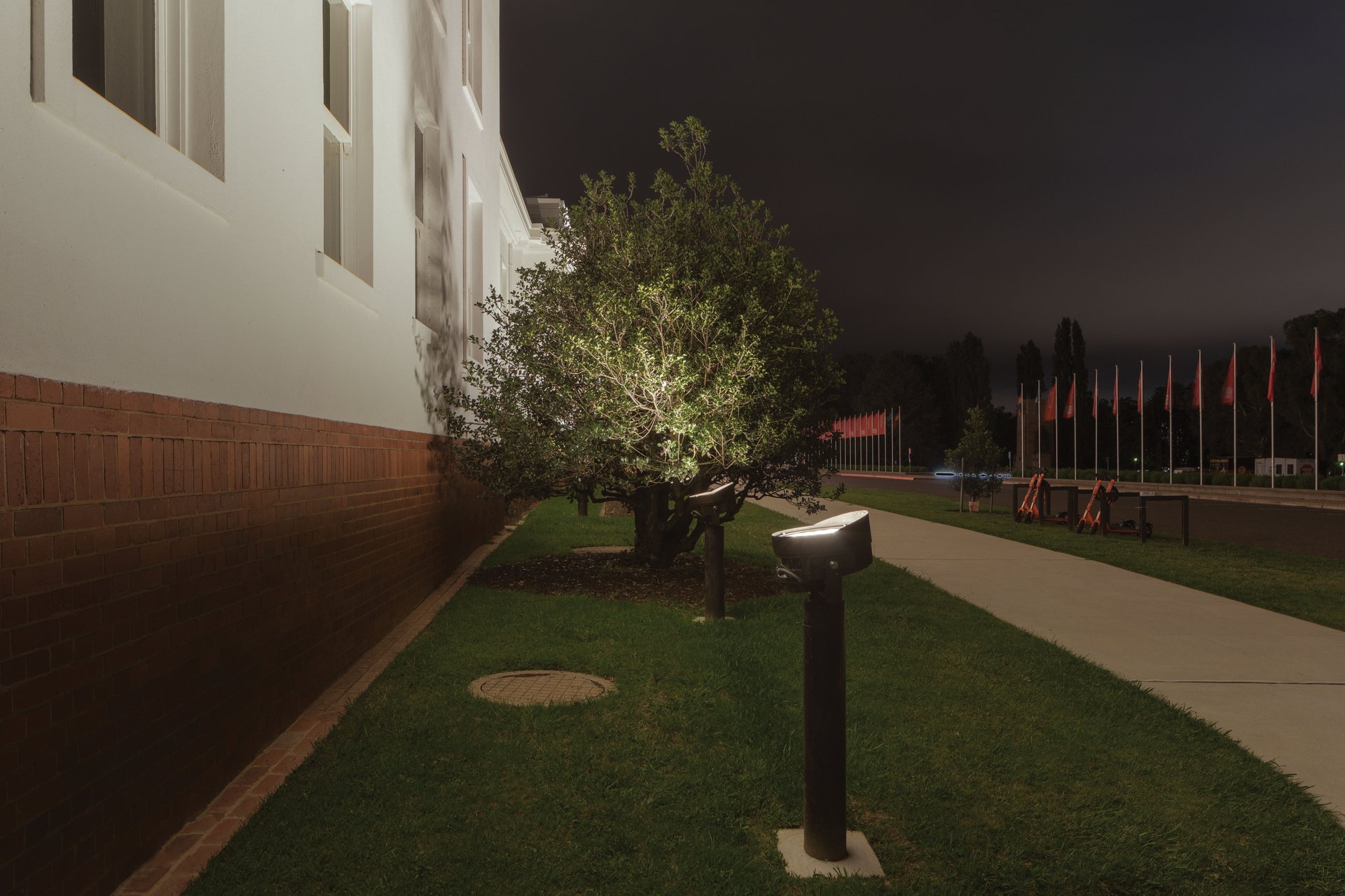 Old Parliament House Canberra at night showing stark white stripped classical architecture designed by first Commonwealth Government architect John Smith Murdoch in 1920s, WE-EF FLC200-CC color-changing projectors providing uniform white wallwash illumination as baseline for dynamic DMX-controlled color effects, National Heritage-listed building serving as Museum of Australian Democracy completed 2020, replacing old halogen floodlights with energy-efficient LED technology designed by WSP lighting designers Anthony Linard and Rachel Thomson