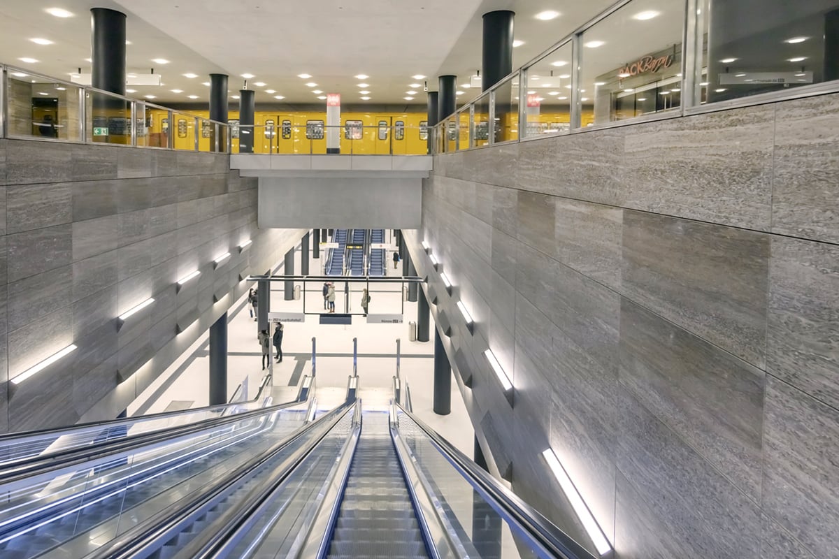 Beleuchtete Rolltreppe in der U-Bahn-Station „Unter den Linden“ in Berlin, die zwei verschiedene Ebenen mit Bahnsteigen verbindet.