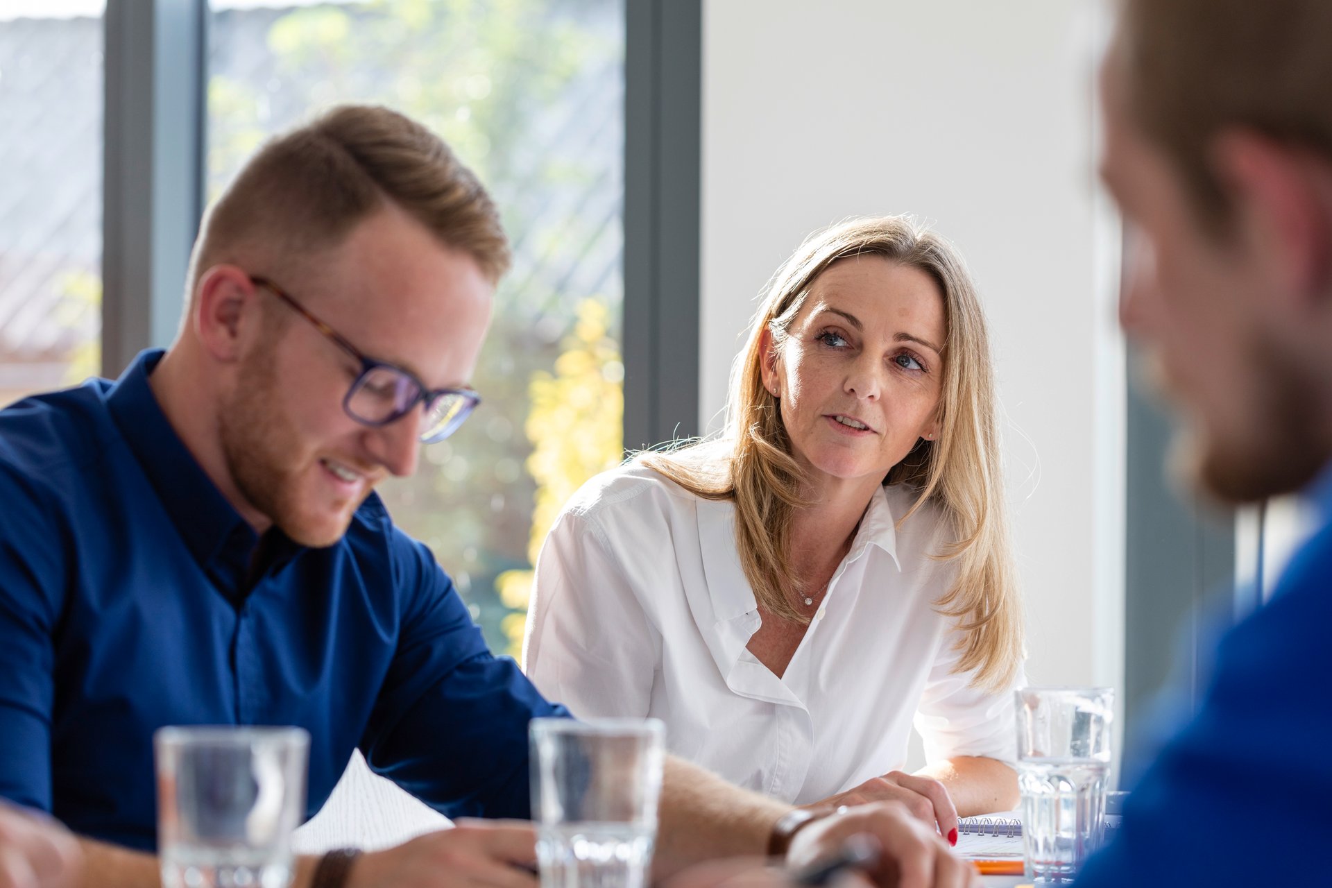 Des employés de WE-EF dans un bureau moderne discutent de concepts et s’écoutent mutuellement.