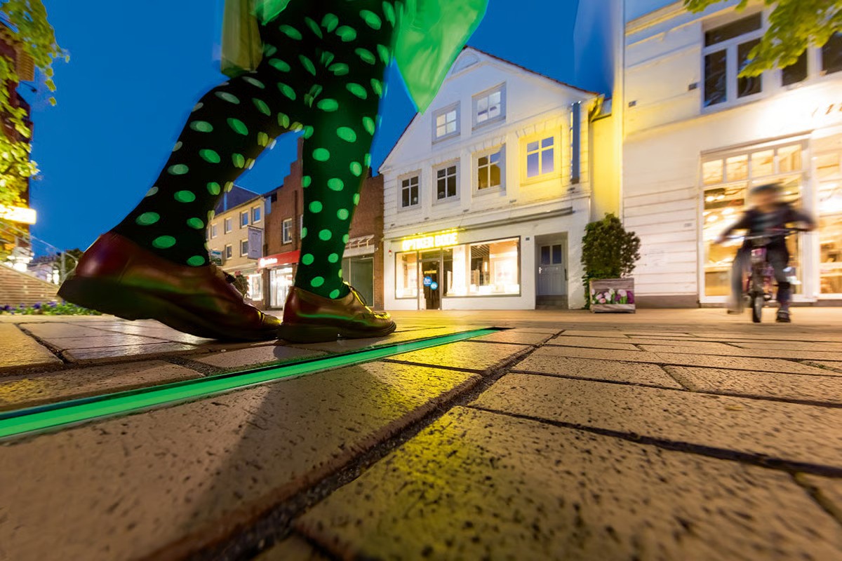 WE-EF ETV130 inground luminaires with green LED creating linear light line in pedestrian lane leading to town hall Elmshorn Germany